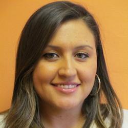 A headshot of Claudia Sandoval against a burnt orange background